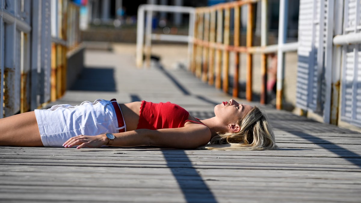 A blonde woman in a red top enjoys sunbathing on a wooden pier in Croatia.